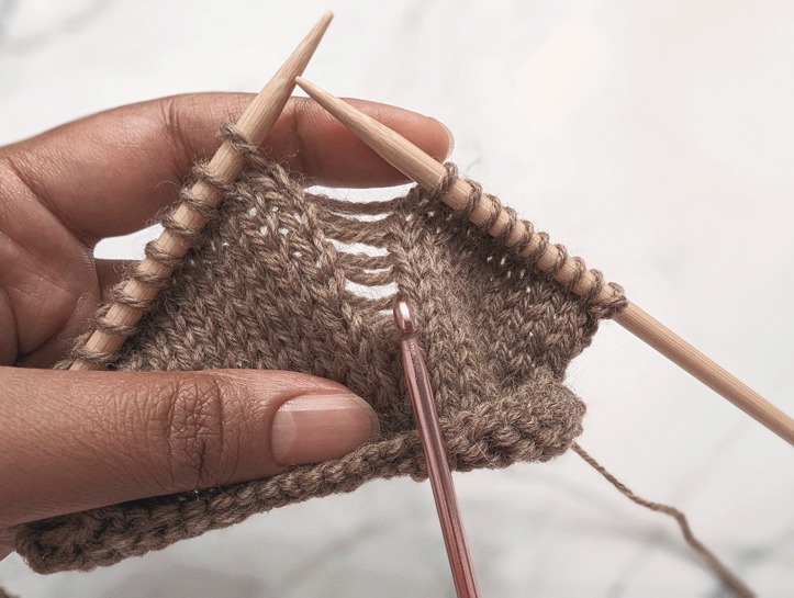 a crochet hook inserted into a dropped stitch preparing to be worked