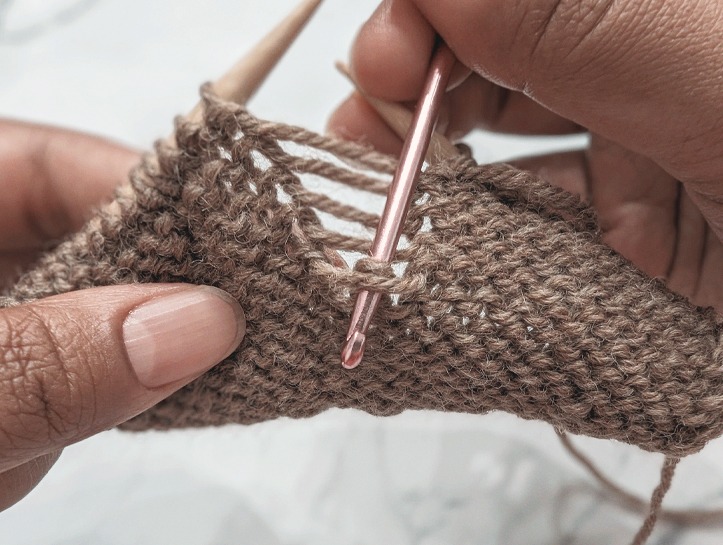 crochet hook inserted into a dropped purl stitch from top to bottom