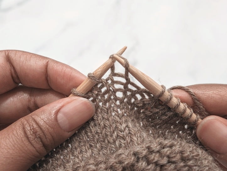 two hands placing the resulting stitch back onto the left hand needle