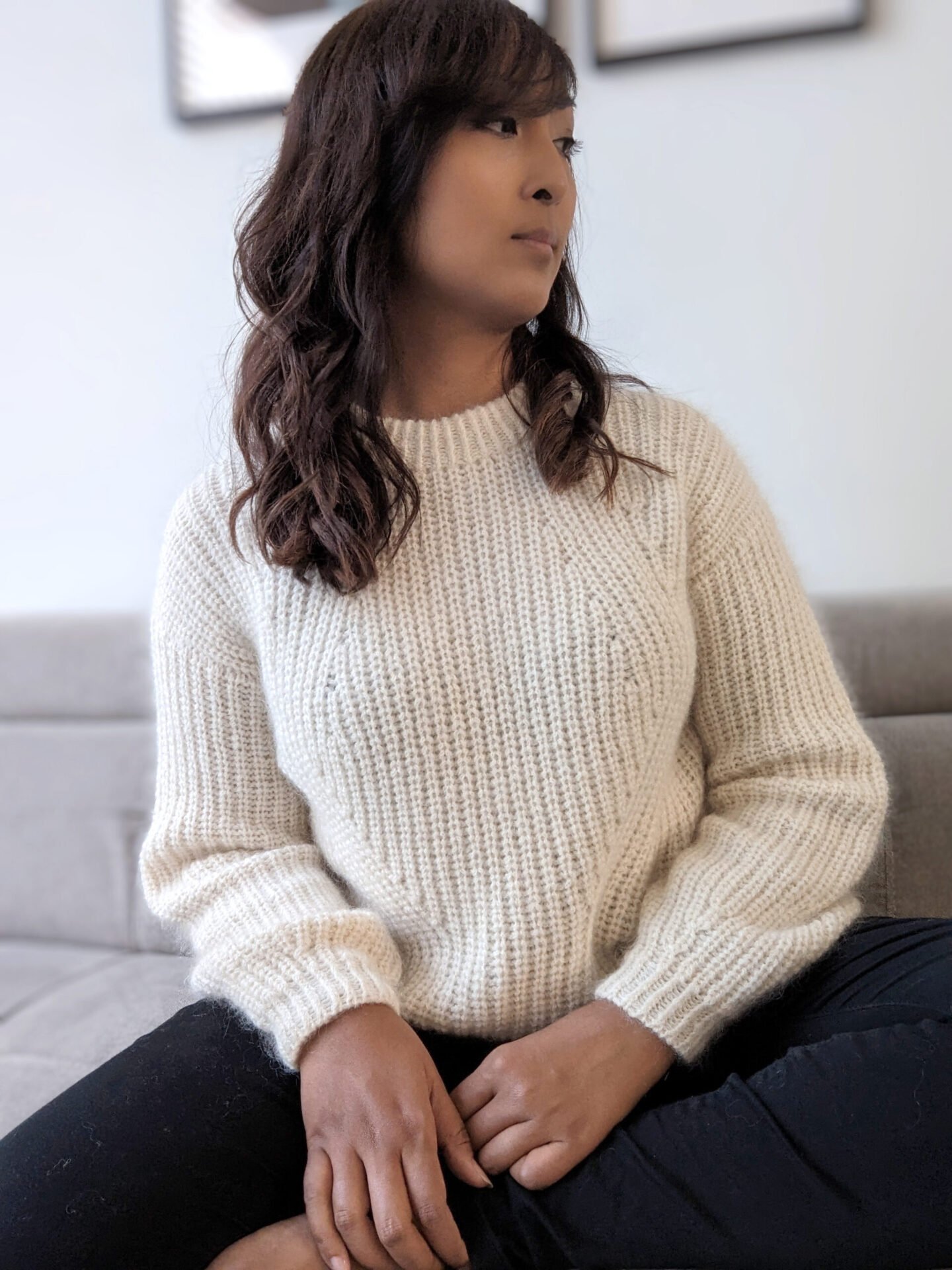 woman sitting on a couch wearing a white ribbed sweater