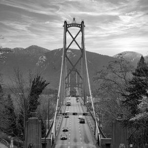 view of Lion's Gate Bridge in Vancouver with mountains in the background and cars driving on road